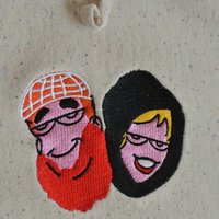 hoodie detail of an embroidery of archie and betty faces made to look like traditional arabic people