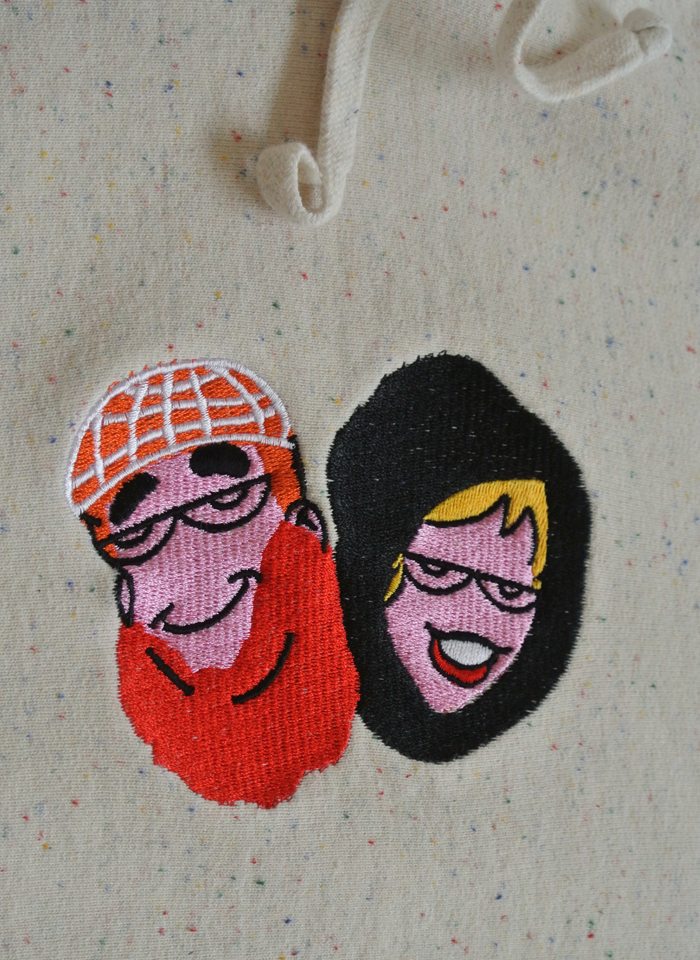 hoodie detail of an embroidery of archie and betty faces made to look like traditional arabic people